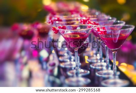 Beautiful line of different colored alcohol cocktails with mint on a open air party, tequila, martini, vodka, and others on decorated catering bouquet table on open air event, picture with tilt shift