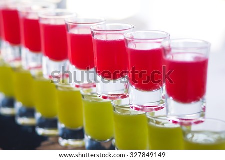 Beautiful row line of different colored alcohol cocktails with mint on a open air party, martini, vodka with bubbles,and others on decorated catering bouquet table on open air event, picture