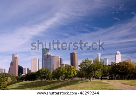 Park view of the Houston skyline with blue sky and clouds.