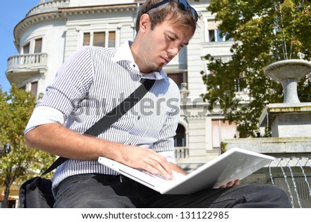 handsome businessman siting outside and using his laptop