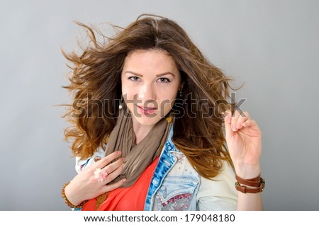 beautiful sexy woman in bright clothes. smiling happy with tousled by wind hair. on a gray background