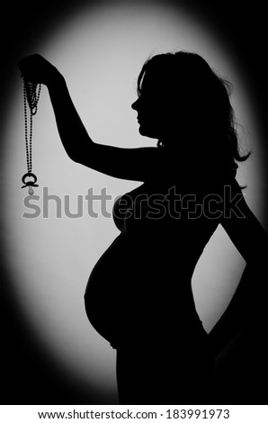 Pregnant woman holding a pacifier on a rope. dark vignetting
