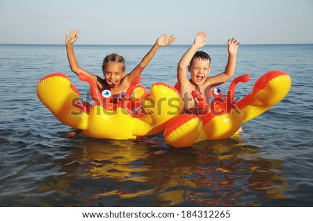 boy and girl laughing and floating on an inflatable mattress in sea