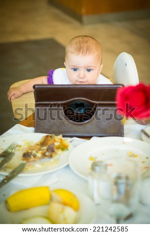baby eats at the table and looking cartoons on the tablet