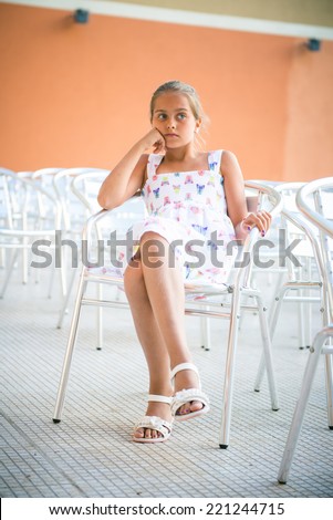 girl sitting on a chair of empty chairs