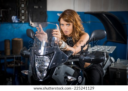 beautiful girl sitting on a motorcycle in the garage