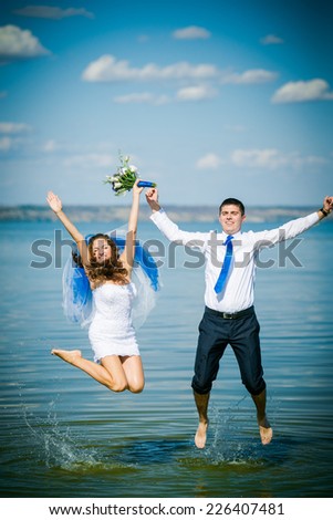 groom and bride jumping for joy on the background of the sea