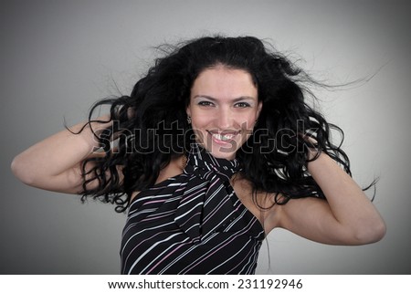 portrait of brunette with curly hair in the studio on a gray background. The wind ruffled her hair