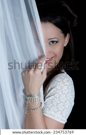 Shy woman hiding behind a white curtain