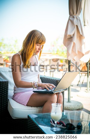 Beautiful smiling woman working on laptop. thoughtful girl working with a laptop on the terrace of the summer cafe