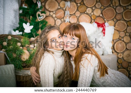 Mother and daughter hugging, winter evening together at home, two girls in sweaters embrace and promote family values. picture of hugging mother and daughter