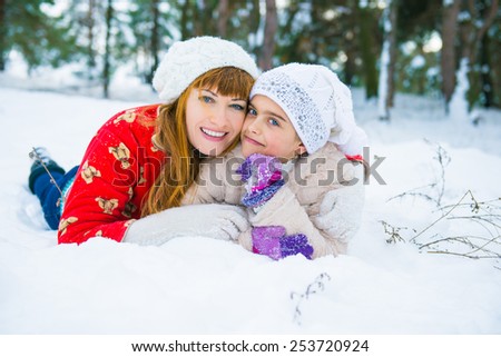 daughter and mother are happy together. Mom and daughter lying on the snow in winter