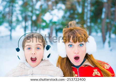 two girls surprised faces on snow background. surprise winter discounts. Mom and daughter in the park in winter, frozen two portraits