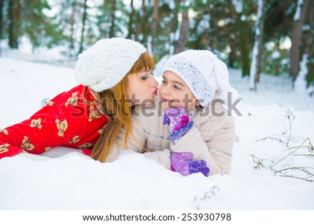 daughter and mother are happy together. Mom and daughter lying on the snow in winter