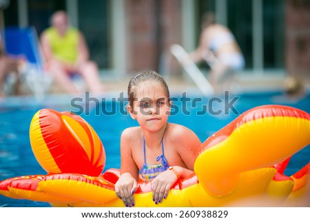 Teenage girl floating on a mattress in the pool. serious girl floats on an inflatable mattress in the form of a crab