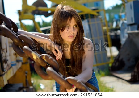 girl with long hair at sunset, young girl among large metallic chains