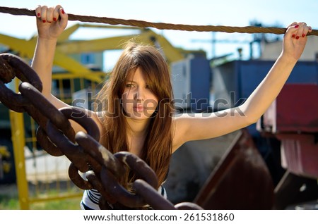 girl with long hair at sunset, young girl among large metallic chains
