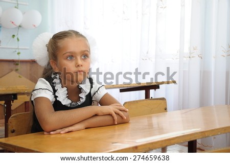 Portrait of lovely girl in classroom. schoolgirl at the desk, little schoolgirl sitting at an empty desk, class 1 exhaust, the girl raised her hand in class