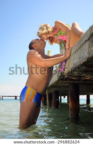 young couple on vacation at sea. man and woman in love. man and woman sitting on the bridge and kiss