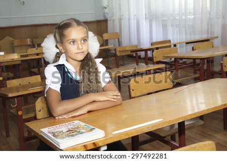 Portrait of lovely girl in classroom. schoolgirl at the desk, little schoolgirl sitting at an empty desk, class 2 exhaust, the girl raised her hand in class