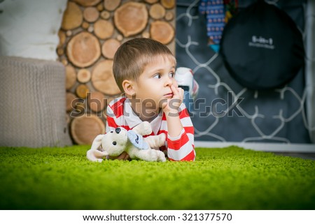 Boy lying on the carpet and picking his nose