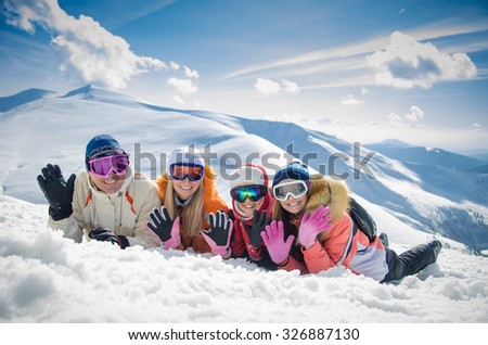 happy family in winter clothes lie on the snow at ski resort