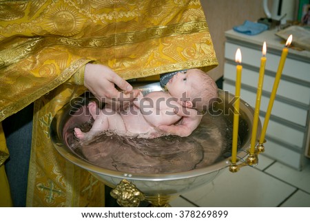 baby christening. Newborn baby in font with hands of priest.  Ceremony of a christening in Christian church. bathing the baby into the baptismal font