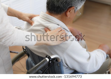 Massage to old man in a wheelchair helper