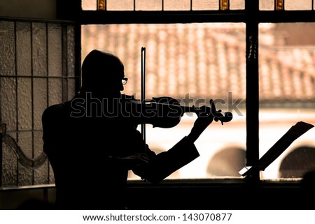 silhouette of professional violinist playing violin.orange filter added