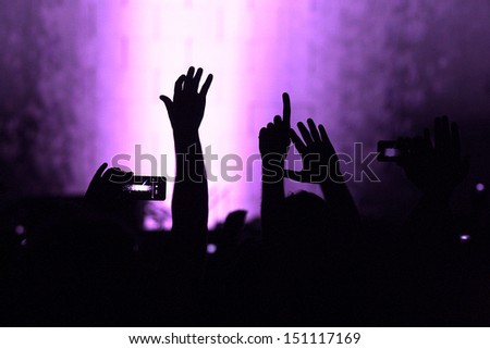 cheering crowd at a rock concert.silhouettes of hands up.purple filter added