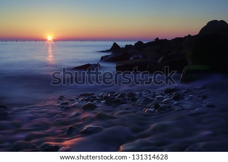Last sun rays over the sea at sunset, long exposure