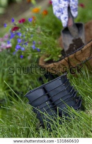 empty flower containers focus on empty flower containers. gardener has planted flowers in coco wire basket in background out of focus.