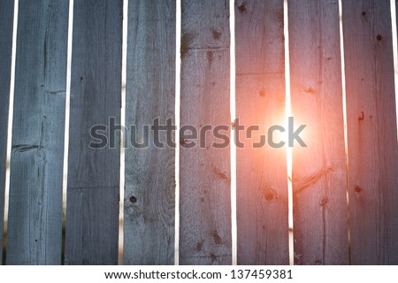 Sun Flare through Fence. the sun peeks through breaks in the old fence.
