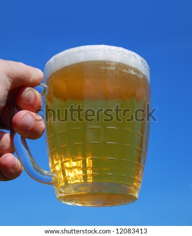 Hand with beer mug over a blue background