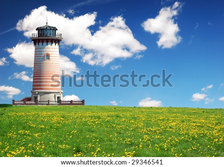 Stone lighthouse on the green field over blue sky