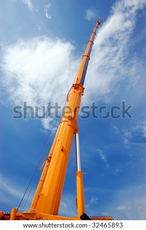 Yellow tall hydraulic crane over blue sky