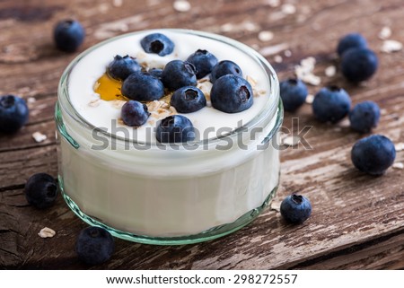 Serving of Yogurt with Whole Fresh Blueberries and Oatmeal on Old Rustic Wooden Table. Closeup Detail.