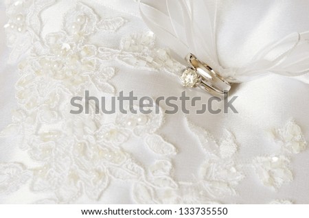 Wedding and engagement rings on a white satin pillow