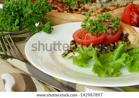 Pie with spinach and cheese served on plate with salad and tomatoes