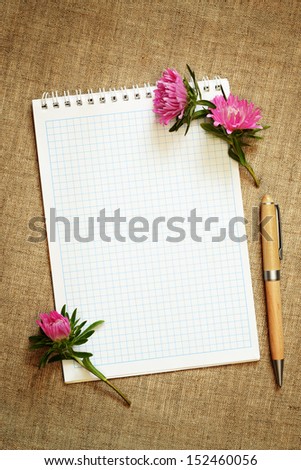 Aster flower buds and a notepad on canvas background