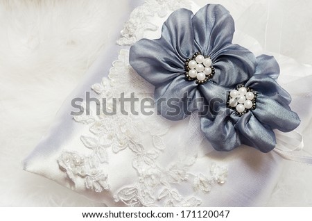 Blue textile flowers on white satin pillow