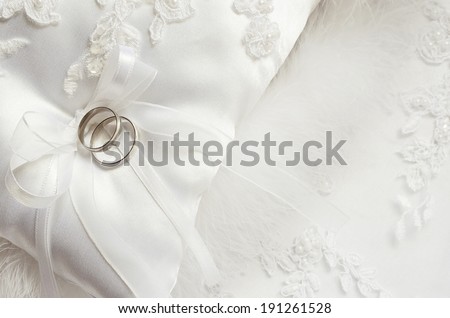 Wedding rings on white satin pillow