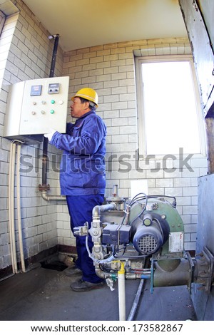 TANGSHAN - DECEMBER 20: Technical personnel adjustment automatic gas type control device, in a manufacturing enterprise, on December 20, 2013, tangshan city, hebei province, China.