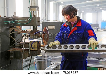 Tangshan - December 22: Worker In Operating Machinery On The Production Line, In A Solar Equipment Production Workshop On December 22, 2013, Tangshan, China.