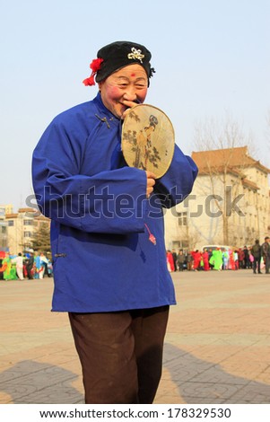 LUANNAN COUNTY - FEBRUARY 8: An old woman wearing purple clothes, performing yangko dance in the street, February 8, 2014, Luannan County, Hebei Province, China.