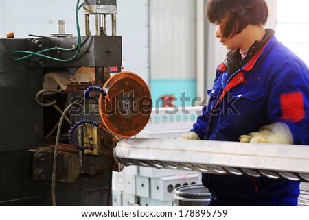 TANGSHAN - DECEMBER 22: Worker in operating machinery on the production line, in a solar equipment production workshop on december 22, 2013, tangshan, china.