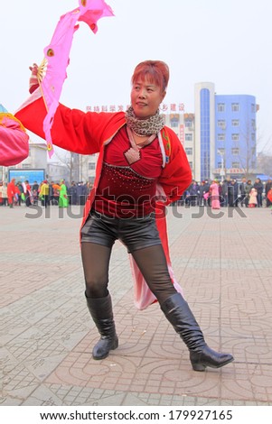 LUANNAN COUNTY - FEBRUARY 15: Young woman wearing colorful clothes, performing yangko dance in the street, during the Chinese Lunar New Year, February 15, 2014, Luannan County, Hebei Province, China.