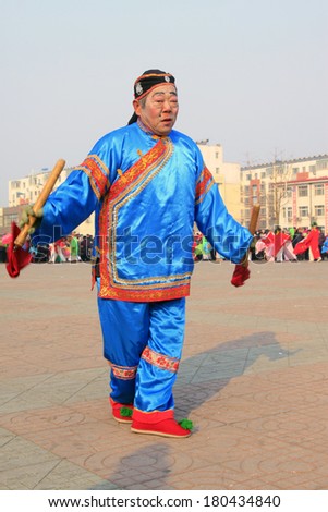 LUANNAN COUNTY - FEBRUARY 12: Old man holding pairs of wooden stick performing yangko dance in the street, during the Chinese Lunar New Year, February 12, 2014, Luannan County, Hebei Province, China.