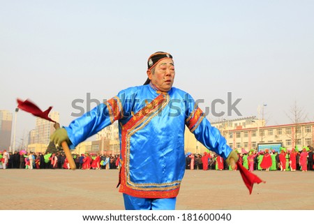 LUANNAN COUNTY - FEBRUARY 12: Old man holding pairs of wooden stick performing yangko dance in the street, during the Chinese Lunar New Year, February 12, 2014, Luannan County, Hebei Province, China.