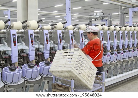 LUANNAN - MAY 4: lady in red working in spinning mill production line, on May 4, 2014, Luannan county, hebei province, China.